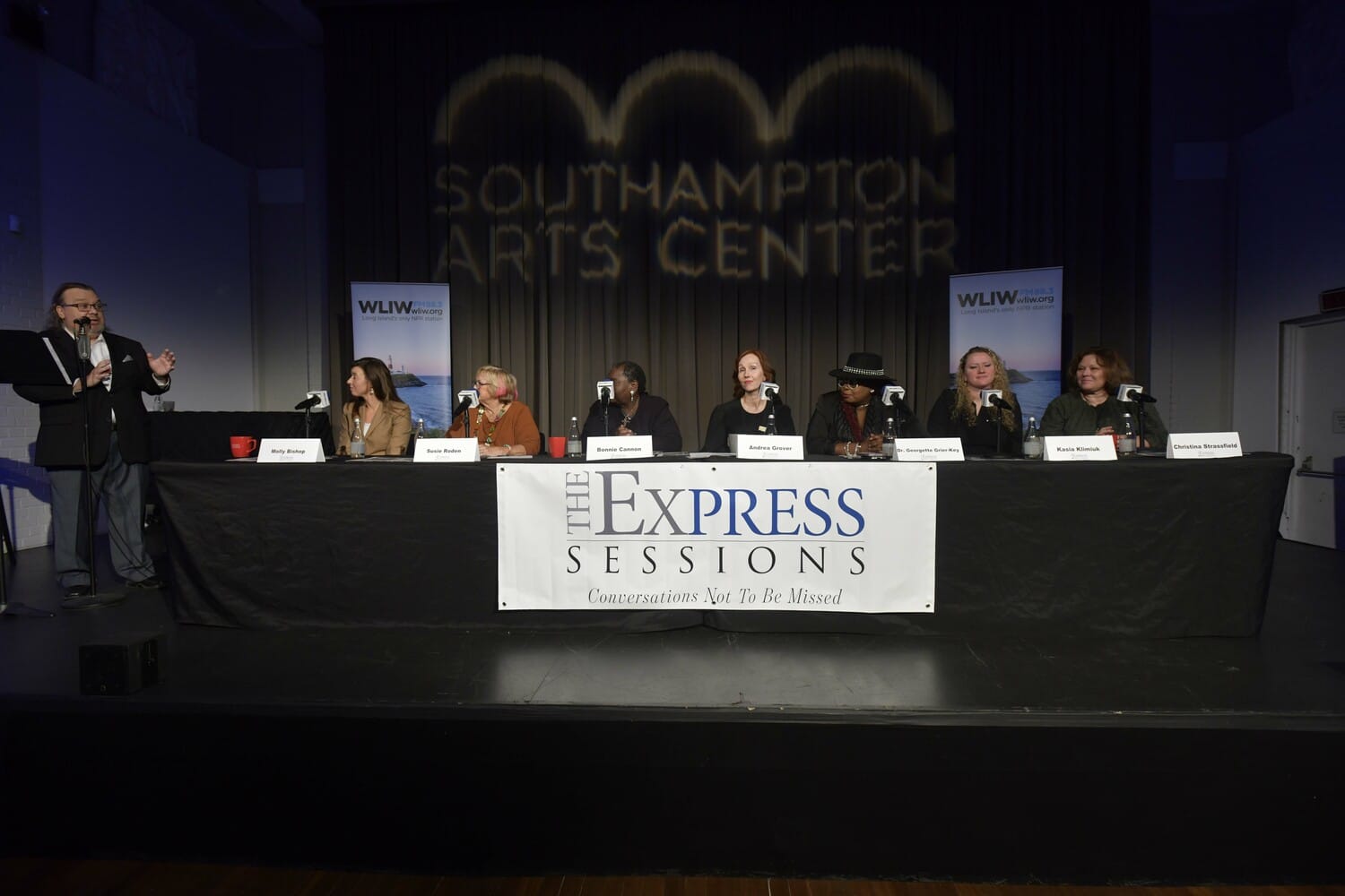 a group of people sitting at a table with microphones