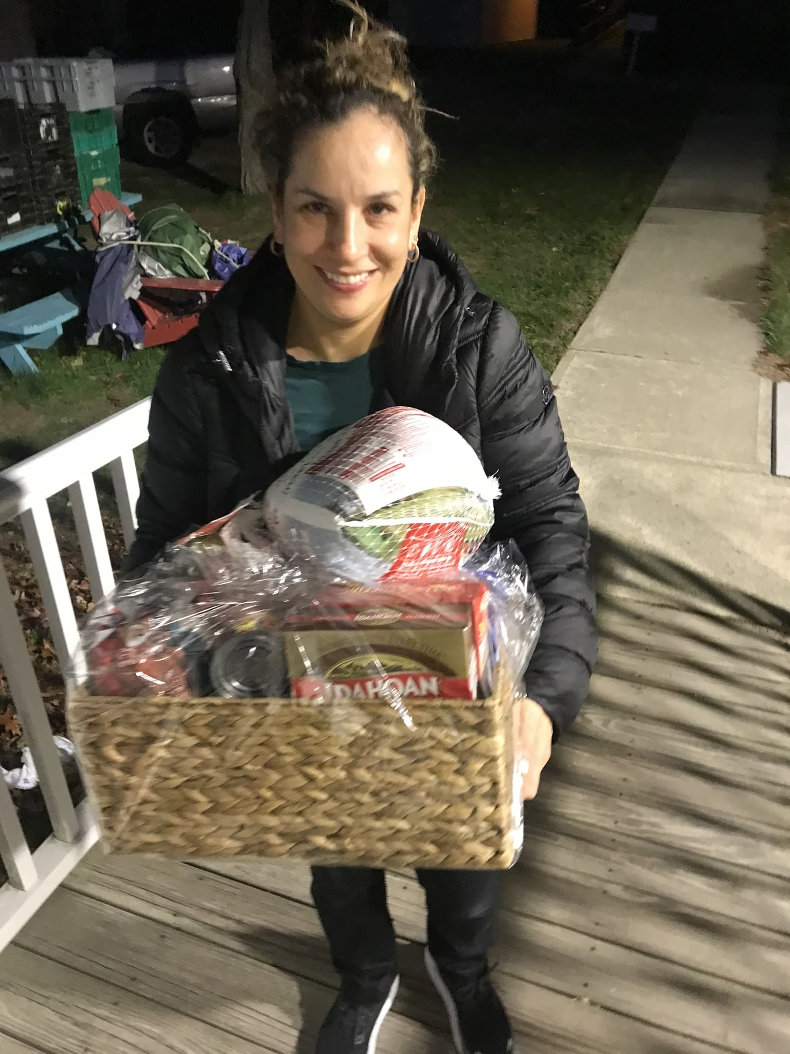 A smiling person holding a basket of food outdoors