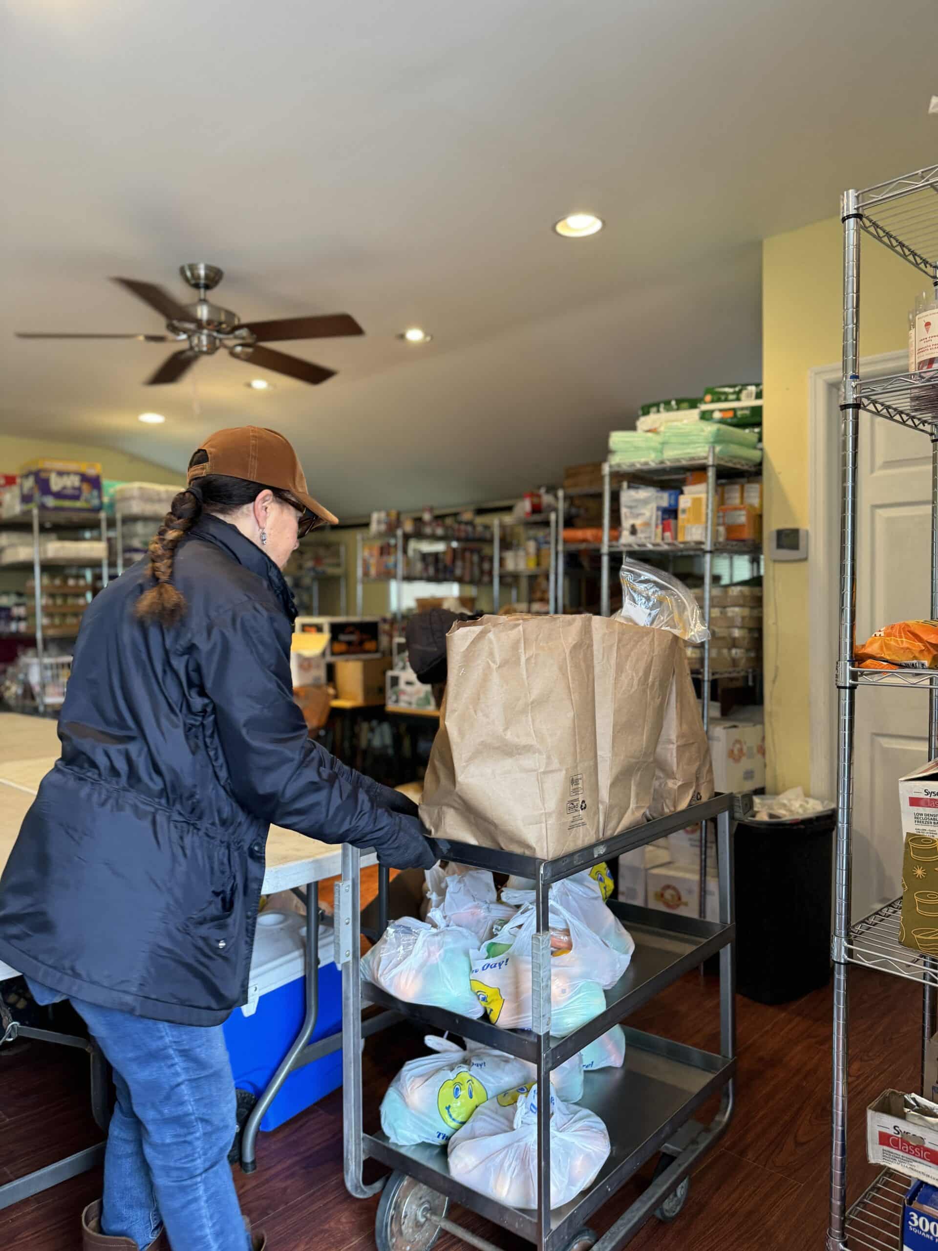 A person arranging food on a cart inside the pantry