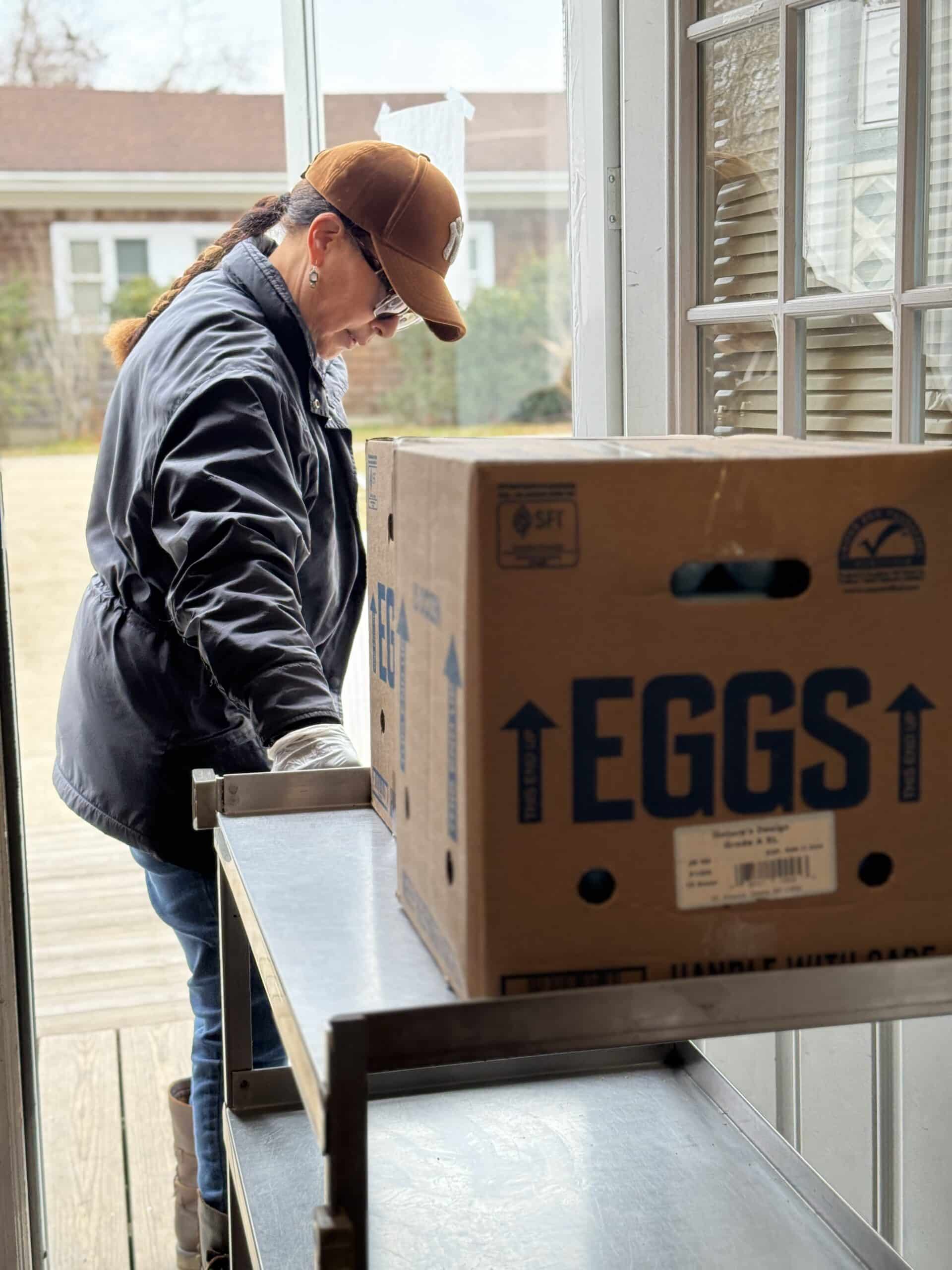 A person handling a box of eggs at the pantry